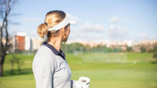Female golfer with sun visor looking at the golf course in Portugal